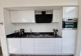 Moderne keukenruimte in Cube Maximaal 4 lodge bij Zuiderzee, Nederland, met witte kasten en apparaten.