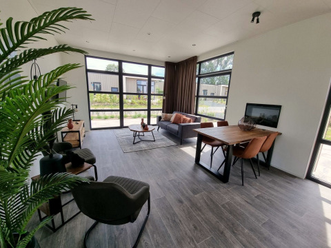 Salon moderne au lodge Cube Maximaal 4 à Zuiderzee, Pays-Bas, avec grandes fenêtres et décoration élégante.