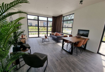 Salón moderno en la cabaña Cube Maximaal 4 en Zuiderzee, Países Bajos, con ventanas grandes y decoración.