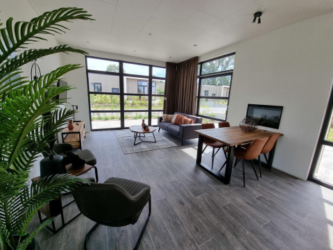 Moderne woonkamer in Cube Maximaal 4 lodge bij Zuiderzee, Nederland, met grote ramen en stijlvolle inrichting.