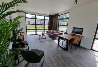Soggiorno moderno nel lodge Cube Maximaal 4 a Zuiderzee, Paesi Bassi, con grandi finestre e arredo.
