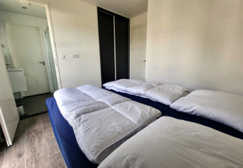 Modernes Schlafzimmer in der Cube Maximaal 4 Lodge am Zuiderzee, Niederlande, mit zwei Betten und weißen Bettdecken.