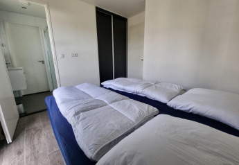 Moderne slaapkamer in de Cube Maximaal 4 lodge aan Zuiderzee in Nederland met twee bedden en witte donsdekens.
