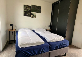 Camera da letto al Cube Maximaal 4 a Zuiderzee, Paesi Bassi, con due letti singoli e arredo moderno essenziale.