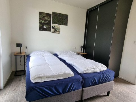 Schlafzimmer im Cube Maximaal 4 bei Zuiderzee, Niederlande, mit zwei Einzelbetten und moderner Einrichtung.