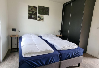 Camera da letto al Cube Maximaal 4 a Zuiderzee, Paesi Bassi, con due letti singoli e arredo moderno essenziale.