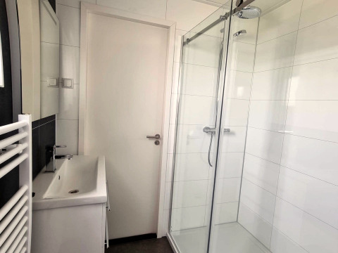 Salle de bain moderne au Cube Maximaal 4 à Zuiderzee, Pays-Bas, avec douche vitrée et lavabo blanc.