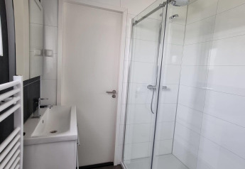 Moderne badkamer in Cube Maximaal 4 te Zuiderzee, Nederland, met glazen douche en stijlvol lavabomeubel.