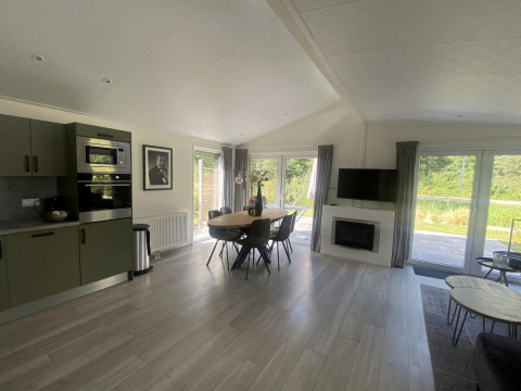 Sala y cocina moderna en el lodge Hackfort MIVA en Zuiderzee, Países Bajos, con mesa de comedor y ventanas grandes.