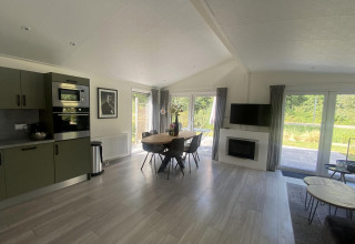 Sala y cocina moderna en el lodge Hackfort MIVA en Zuiderzee, Países Bajos, con mesa de comedor y ventanas grandes.