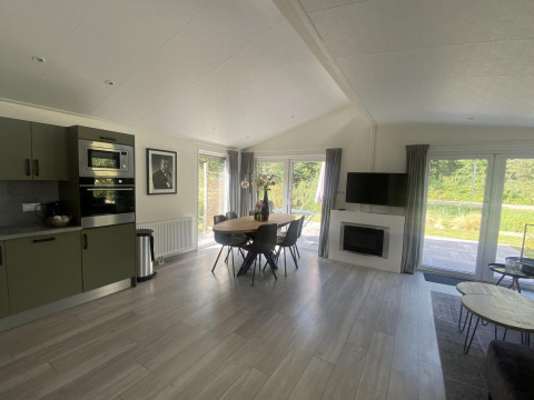 Moderne woonkamer en keuken in het Hackfort MIVA lodge bij Zuiderzee, Nederland, met tafel en grote ramen.
