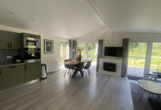 Moderne woonkamer en keuken in het Hackfort MIVA lodge bij Zuiderzee, Nederland, met tafel en grote ramen.