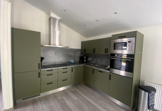 Cocina moderna en el lodge Hackfort MIVA en Zuiderzee, Países Bajos, con armarios verdes y electrodomésticos.