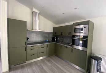 Moderne keuken in het Hackfort MIVA lodge bij Zuiderzee, Nederland, met groene kasten en inbouwapparatuur.