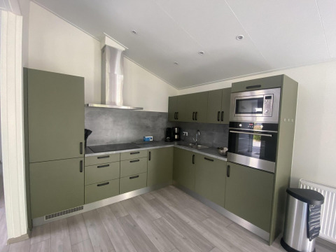 Moderne keuken bij Hackfort MIVA-lodge aan Zuiderzee, Nederland, met groene kasten en inbouwtoestellen.