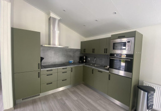 Moderne keuken bij Hackfort MIVA-lodge aan Zuiderzee, Nederland, met groene kasten en inbouwtoestellen.
