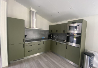 Moderne køkkenfaciliteter på Hackfort MIVA lodge ved Zuiderzee, Holland, med grønne skabe og ståludstyr.