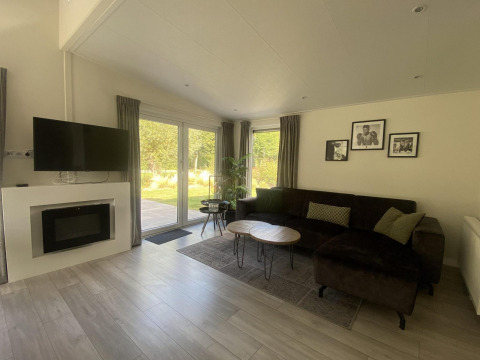 Woonkamer van Hackfort MIVA-lodge aan het Zuiderzee in Nederland met bank, tv en uitzicht op tuin.
