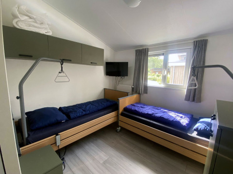 Dos camas individuales con ropa de cama azul en una habitación luminosa de Hackfort MIVA lodge, Zuiderzee, Países Bajos.