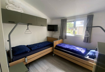 Twee eenpersoonsbedden met blauw beddengoed in een lichte kamer bij Hackfort MIVA lodge, Zuiderzee, Nederland.