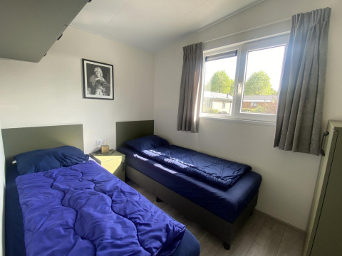 Two single beds with blue bedding in a bright room at Hackfort MIVA lodge at Zuiderzee, Netherlands.