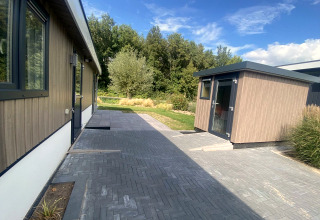 Vista exterior del lodge Hackfort MIVA en Zuiderzee, Países Bajos, con camino y vegetación alrededor.