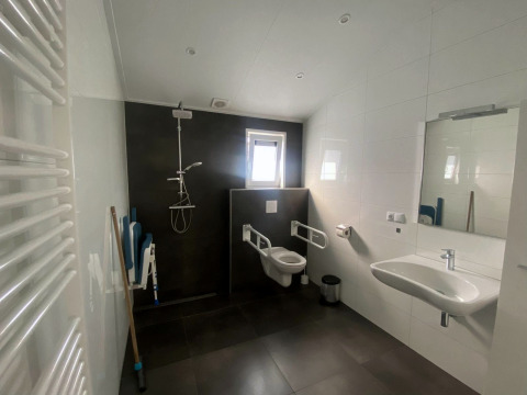 Baño accesible en la casa Hackfort MIVA en Zuiderzee, Países Bajos, con ducha, inodoro y lavabo modernos.