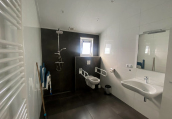 Aangepaste badkamer in Hackfort MIVA-lodge aan de Zuiderzee, Nederland, met douche, toilet en wastafel.
