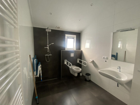 Aangepaste badkamer in Hackfort MIVA-lodge aan de Zuiderzee, Nederland, met douche, toilet en wastafel.