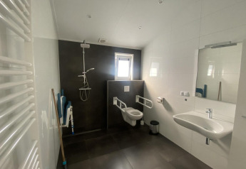 Handicapvenligt badeværelse på Hackfort MIVA-lodge i Zuiderzee, Holland, med bruser, toilet og håndvask.