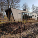Moderne tiny house ved navn Just Nature 4 omgivet af natur, hegn og træer under klar himmel.