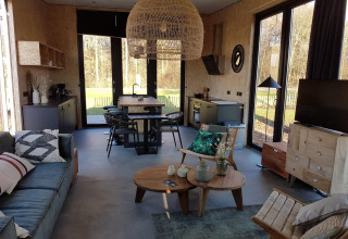 Soggiorno e cucina moderni in una tiny house a Zuiderzee, Paesi Bassi, con grandi finestre e arredo naturale.