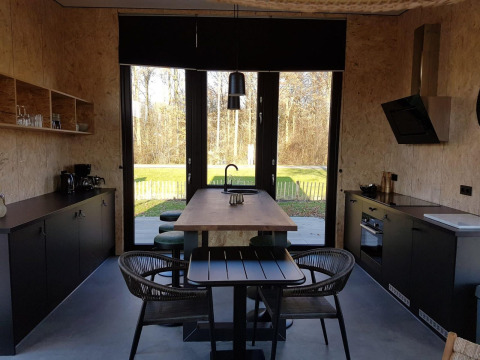 Moderne tiny house keuken en eethoek met grote ramen en zicht op de natuur in Just Nature 4, Zuiderzee.