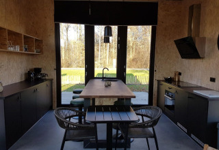 Moderne tiny house keuken en eethoek met grote ramen en zicht op de natuur in Just Nature 4, Zuiderzee.