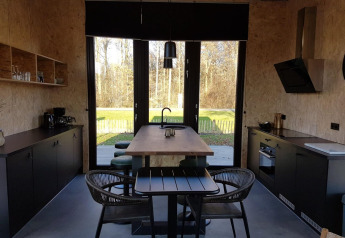 Moderne tiny house keuken en eethoek met grote ramen en zicht op de natuur in Just Nature 4, Zuiderzee.