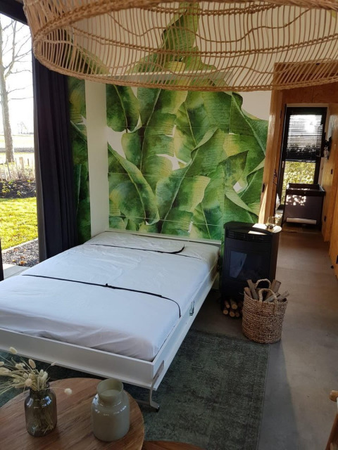 Tiny house moderna con murale di foglie verdi, letto matrimoniale e vista natura a Just Nature 4, Zuiderzee.