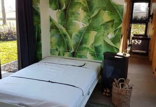 Tiny house moderna con murale di foglie verdi, letto matrimoniale e vista natura a Just Nature 4, Zuiderzee.