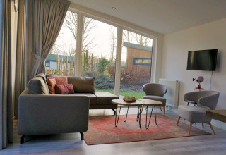 Moderne lounge med store vinduer, grå sofa og udsigt over have i Pavilion 4, Zuiderzee, Holland.