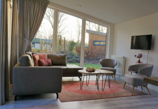 Salon moderne avec grandes fenêtres, canapé gris et vue sur jardin dans le Pavilion 4, Zuiderzee, Pays-Bas.