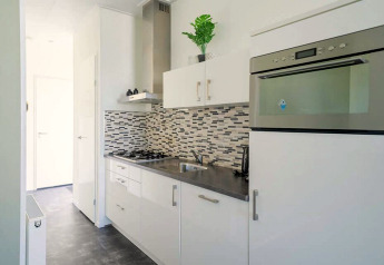 Cuisine moderne et compacte du Pavilion 4 à Zuiderzee, Pays-Bas, avec des placards blancs et une crédence en mosaïque.