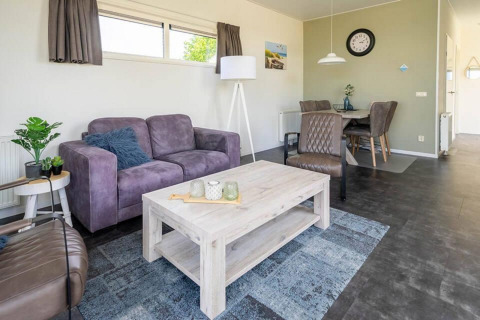 Modernes Wohnzimmer im Pavilion 4 bei Zuiderzee, Niederlande, mit lila Sofa, Esstisch und hellen Möbeln.