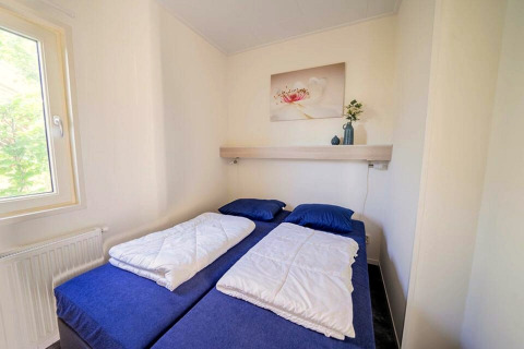 Lyst og kompakt soveværelse med to enkeltsenge, blå sengetøj og dekoration i Pavilion 4, Zuiderzee.