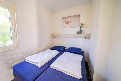 Chambre lumineuse et compacte avec deux lits simples, literie bleue, dans le Pavilion 4 à Zuiderzee, Pays-Bas.