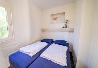 Compacte, lichte slaapkamer met twee eenpersoonsbedden, blauwe beddengoed in Pavilion 4 te Zuiderzee.