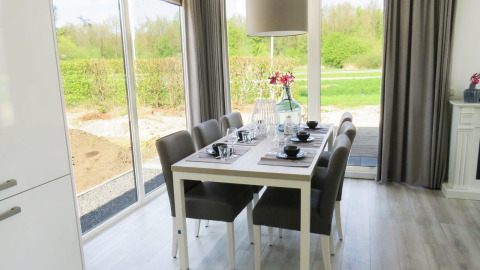 Eethoek in het Pavilion bij Zuiderzee, Nederland, met modern interieur en uitzicht op de tuin buiten.