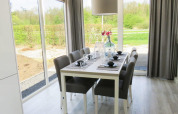Dining area at Pavilion at Zuiderzee, Netherlands, with modern decor and scenic outdoor garden views.