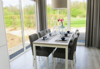 Eethoek in het Pavilion bij Zuiderzee, Nederland, met modern interieur en uitzicht op de tuin buiten.