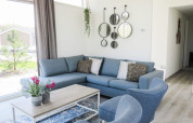 Modern living room at Pavilion at Zuiderzee, Netherlands, with blue sofas, wall mirrors, and large windows.