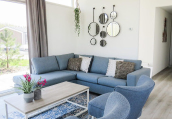 Moderne woonkamer in Pavilion at Zuiderzee, Nederland, met blauwe zetel, ronde spiegels en grote ramen.