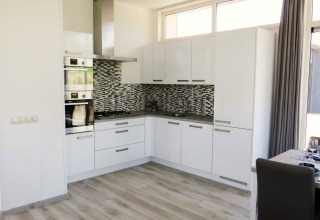 Cuisine moderne avec armoires blanches et carreaux mosaïques, Pavilion at Zuiderzee aux Pays-Bas, coin repas à côté.